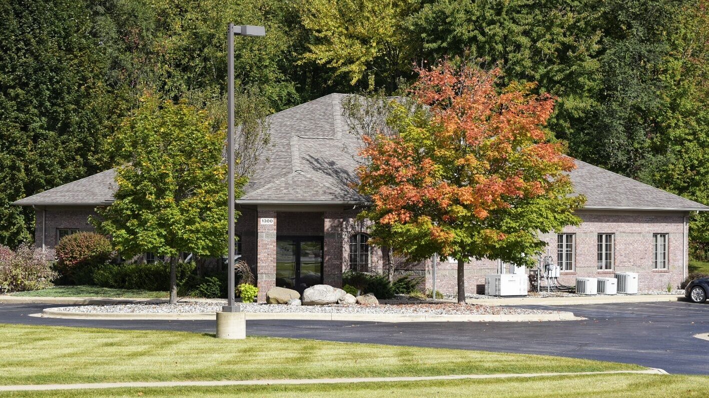 Modern brick building framed by trees displaying fall colors. 